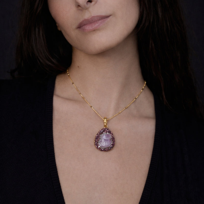 Close-up of the amethyst pendant necklace, showcasing the vibrant purple amethyst stone framed by delicate gold accents. The intricate design highlights the gemstone's natural beauty and the fine craftsmanship of the necklace.