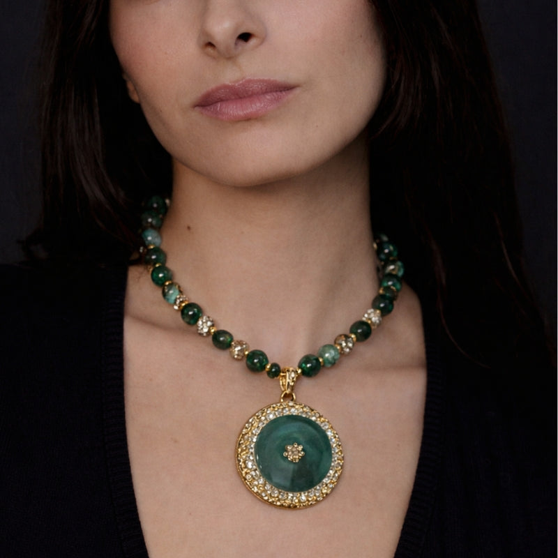 Close-up of the watergrass glass pendant, highlighting the intricate design and the vibrant green agate stone surrounded by delicate gold accents. The craftsmanship and attention to detail make this necklace a stunning statement piece.
